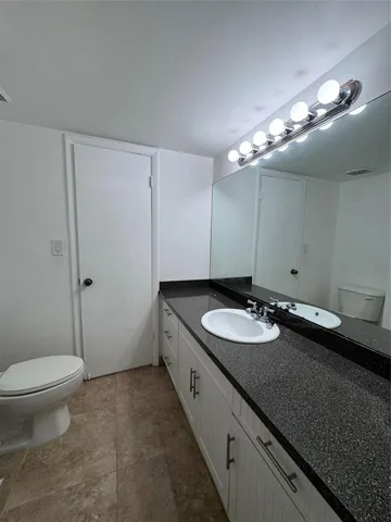 Vanity with a dark speckled countertop, undermount sink, and chrome faucet