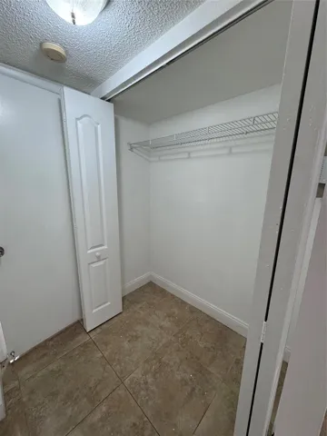 Walk-in closet featuring built-in wire shelving, ceramic tile flooring, and white bifold doors