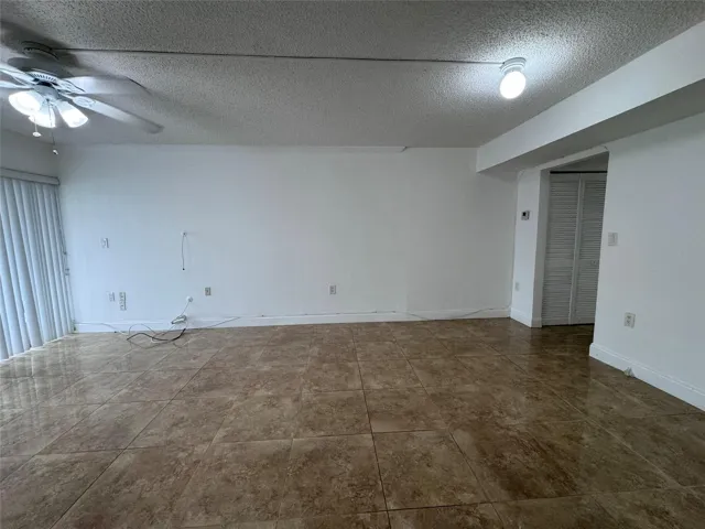 Expansive room with large format tile flooring, a ceiling fan, and a built-in closet with louvered bifold doors