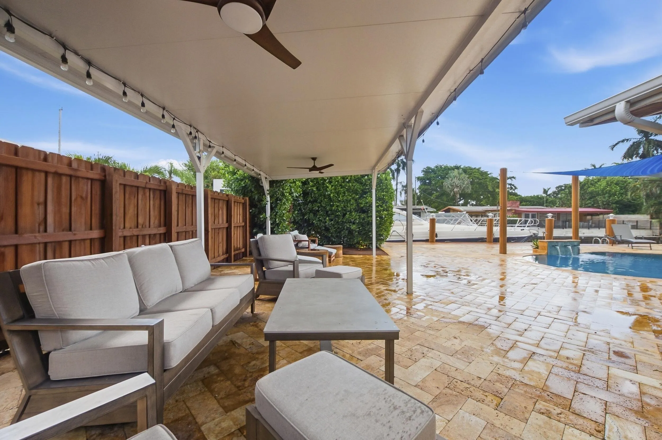 Covered patio with integrated ceiling fans, string lighting, paver patio, and a dedicated pool area