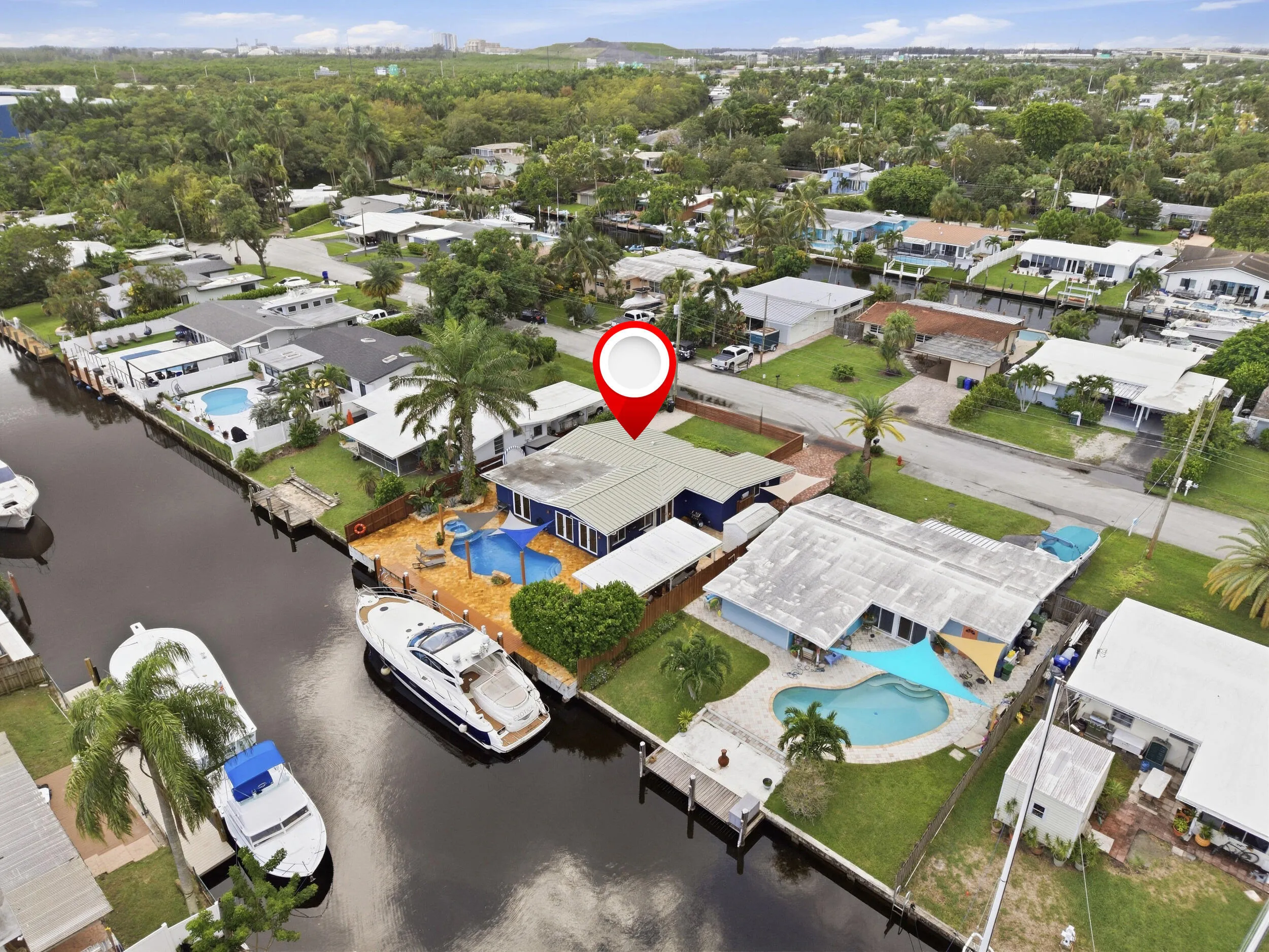 Waterfront property featuring a private boat dock, in-ground swimming pool, and mature palm trees