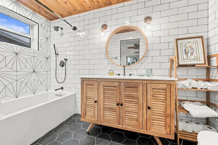 Wood-finish ceiling, white subway tile walls, geometric pattern shower wall tile, deep soaking tub, and hexagon floor tiling