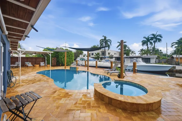 Freeform swimming pool with integrated spa and extensive paver patio
