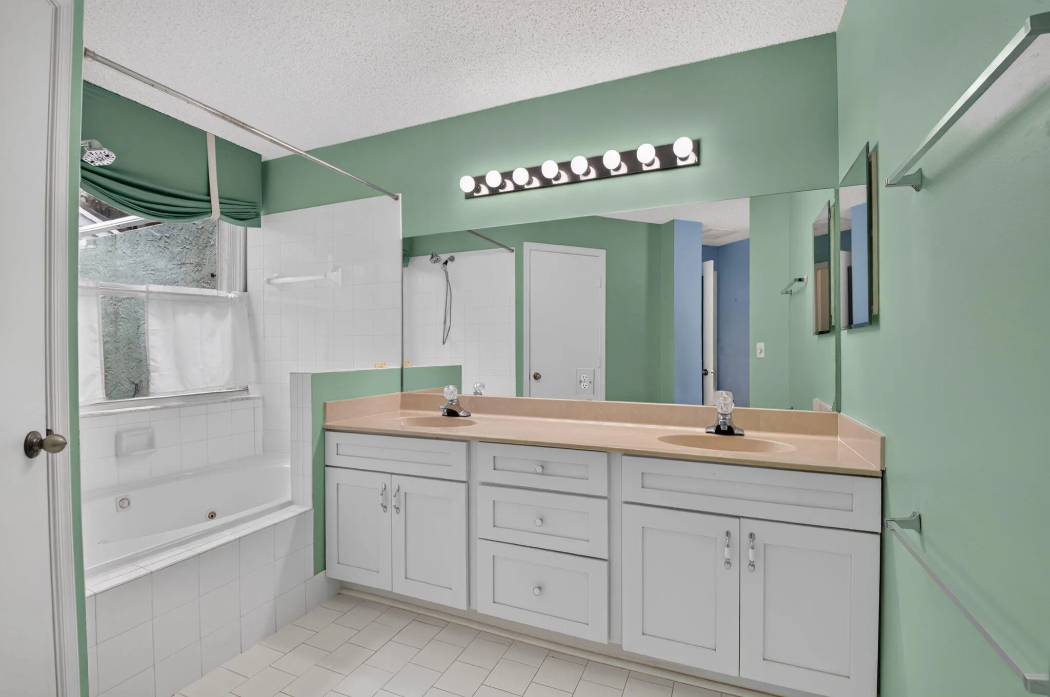 Dual sink vanity with white cabinetry and tile flooring