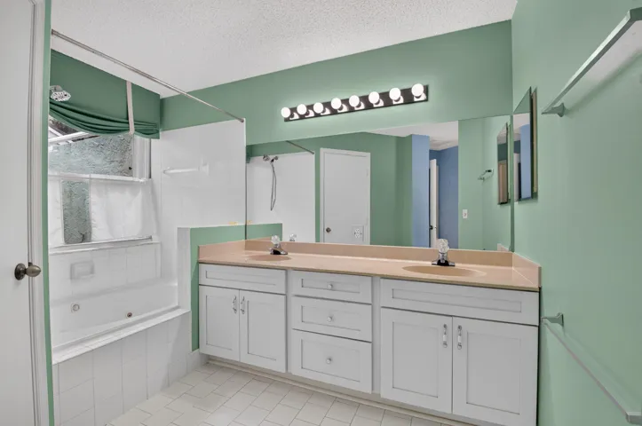 Dual sink vanity with white cabinetry and tile flooring