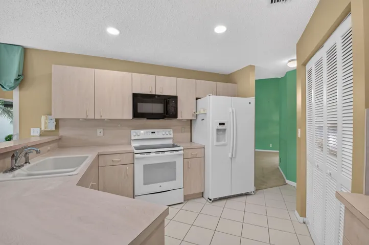 Kitchen featuring light wood-finish cabinetry, tile flooring, recessed lighting