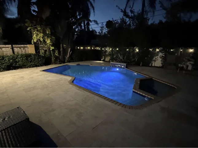 Geometric shape swimming pool with a raised spa, brick coping, and a surrounding paver patio