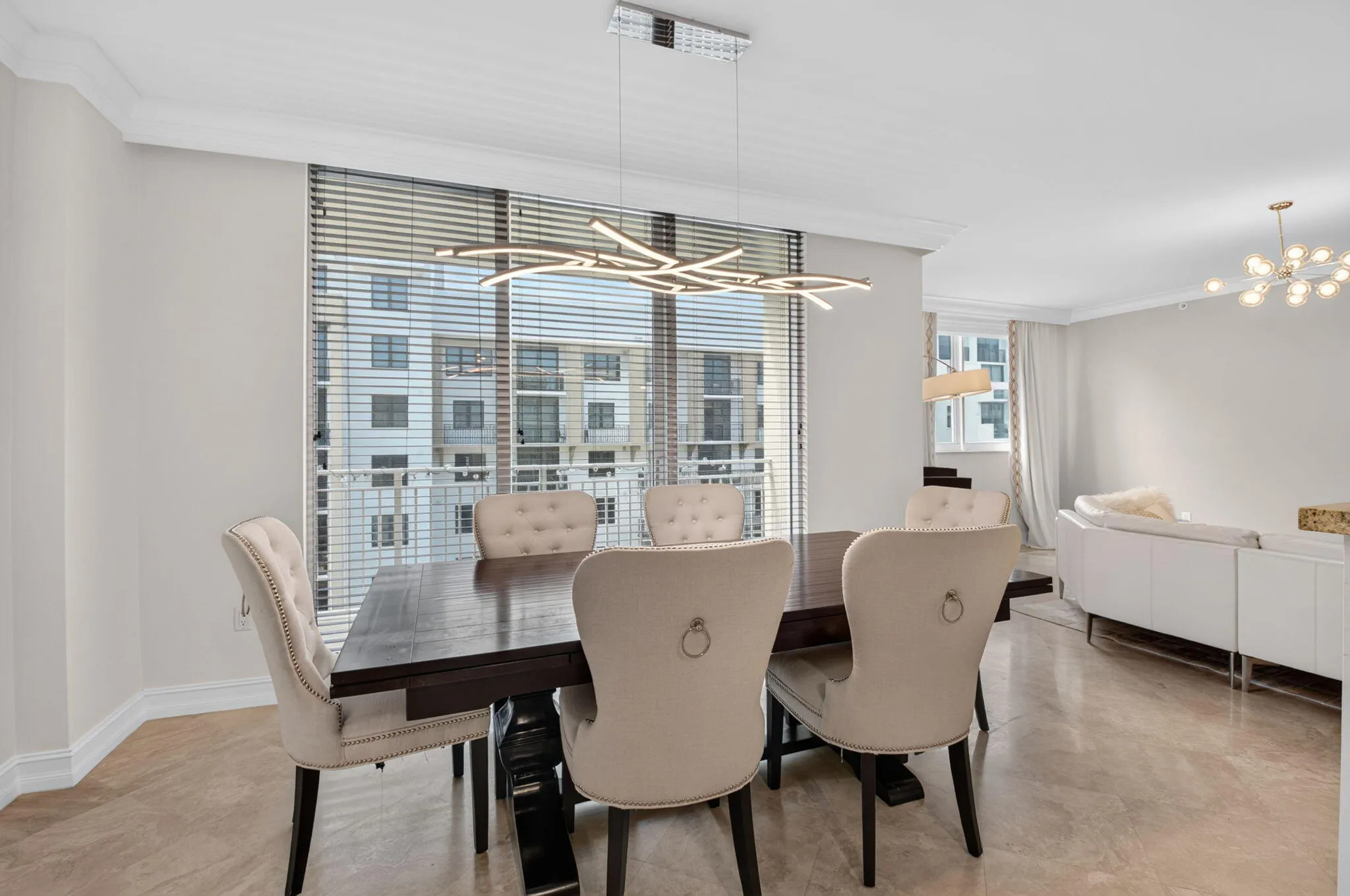 Open-concept living space with light-toned tile flooring, recessed lighting, and crown molding