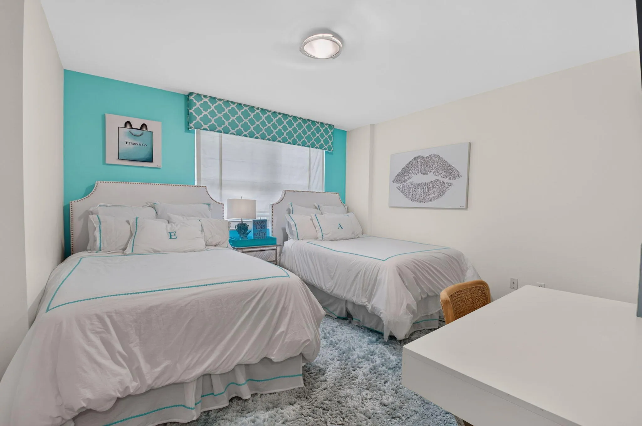 Recessed lighting illuminates a room featuring a full wall of accent color, a window with a patterned valance, and a white desk surface