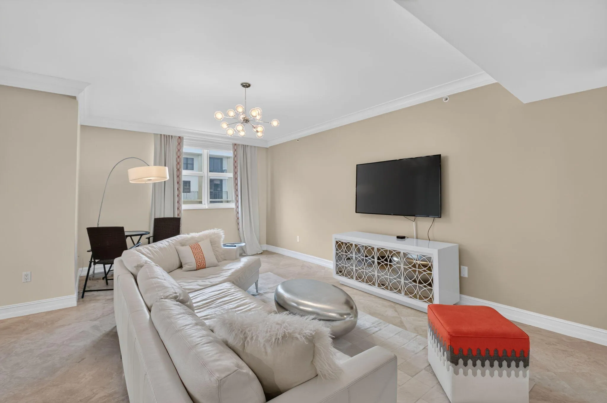 Open-concept living area featuring a modern staircase with wood treads and a cable railing, stone-finish flooring, and crown molding