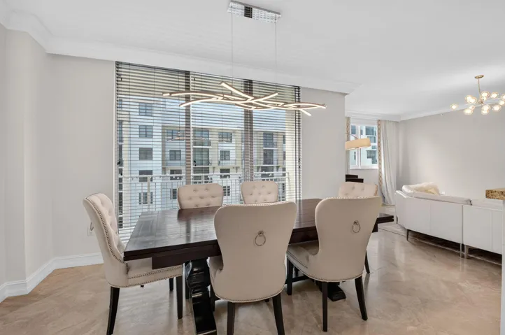Open-concept living space with light-toned tile flooring, recessed lighting, and crown molding