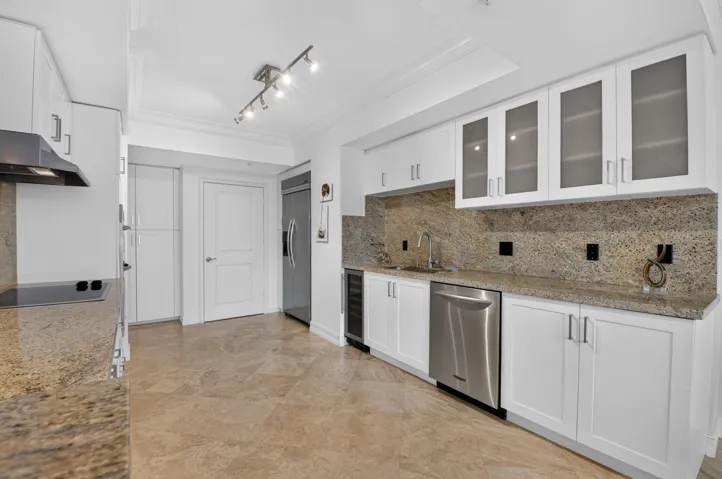White cabinetry with frosted glass accents, stainless steel appliances, a built-in wine refrigerator, and tile flooring