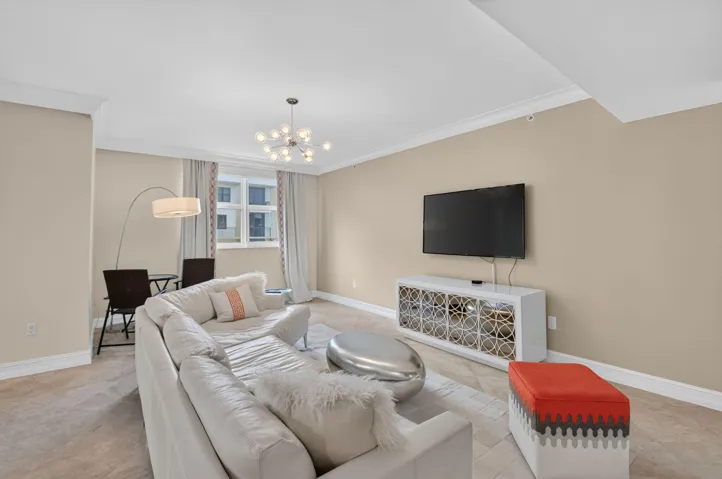 Open-concept living area featuring a modern staircase with wood treads and a cable railing, stone-finish flooring, and crown molding