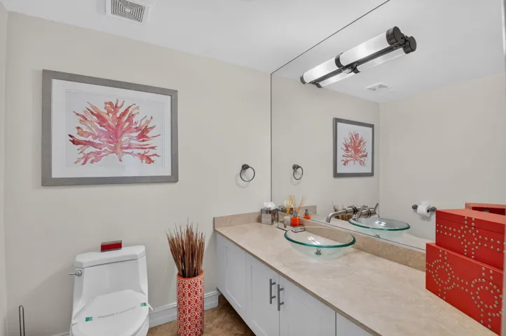 Vanity with a light-toned countertop, dual glass vessel sinks, and a large wall-mounted mirror