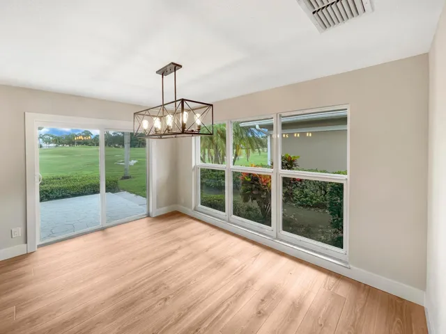Wood-finish flooring, contemporary open-cage chandelier, sliding glass doors, full-length windows, and neutral wall tones