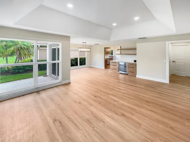 Vaulted ceilings, recessed lighting, wood-finish flooring, built-in wet bar with beverage refrigerator, and sliding glass doors