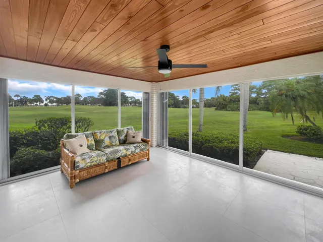 Wood-finish ceiling panels, ceiling fan, tile flooring, full-height windows, and an outdoor patio space