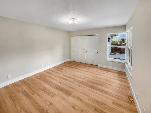 Wood-finish flooring, neutral wall tones, window with natural light, and a flush-mount ceiling light