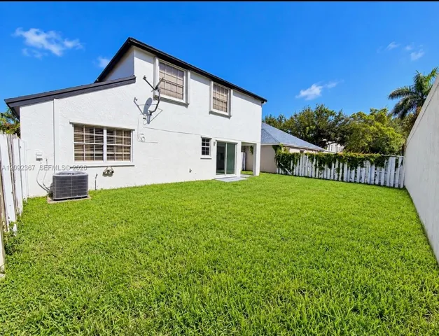 Large private back yard showing sliding glass doors from the kitchen/dining room area.