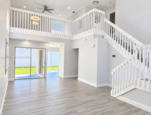 View of Large private fenced back yard from Living/Dining area - and stairway up to Large Loft.