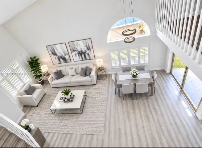 VIRTUAL STAGED - Living and Dining area looking down from upstairs with bay window with Bahama shutters!