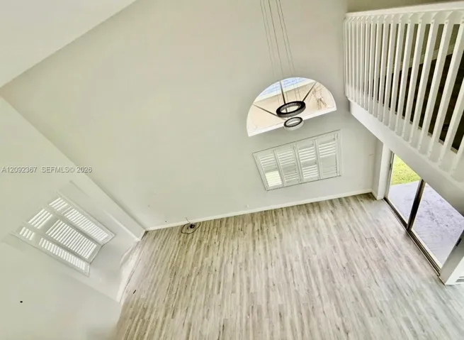 VIRTUAL STAGED - Living and Dining room area looking down from the upstairs - notice bay window in the front and Bahama Shutters on both windows.