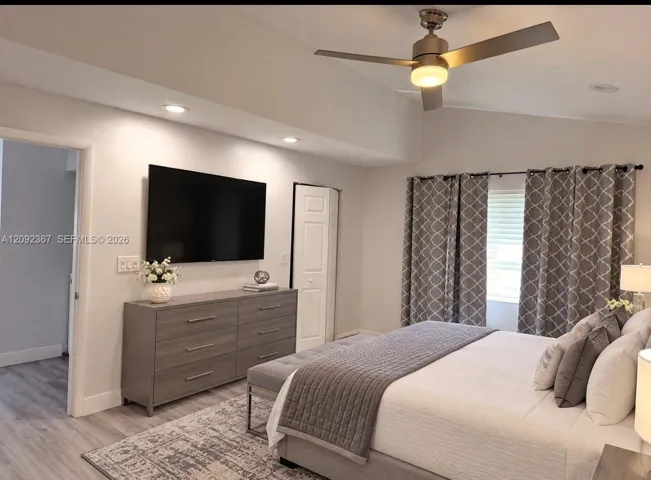 VIRTUAL STAGED - Primary Bedroom on first floor with drapes and walk in closet.