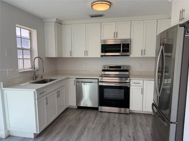 White cabinets - stainless steel appliances - with window and Sliding door to private back yard.