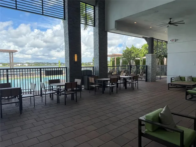 Covered outdoor terrace featuring stone-clad structural pillars, large-format paver flooring, recessed ceiling lighting, and overhead ceiling fans