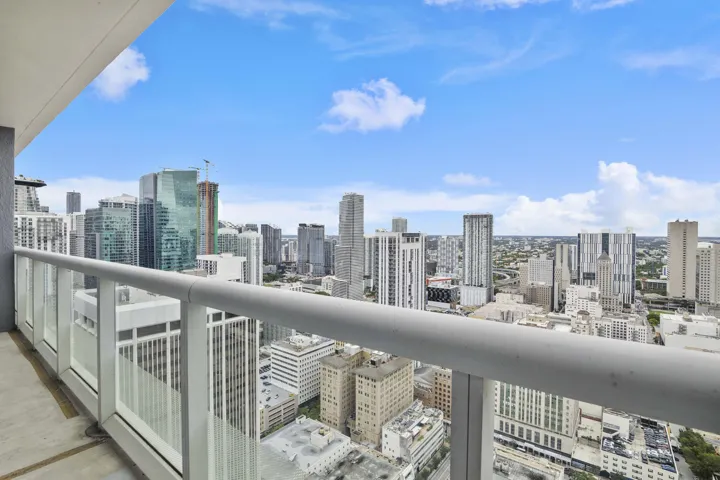 City and sunset line from a real balcony, not a Juliet. Glass rail, open sky, downtown stacked to the horizon. This is why you tour at golden hour. The kitchen and bath are supporting actors.