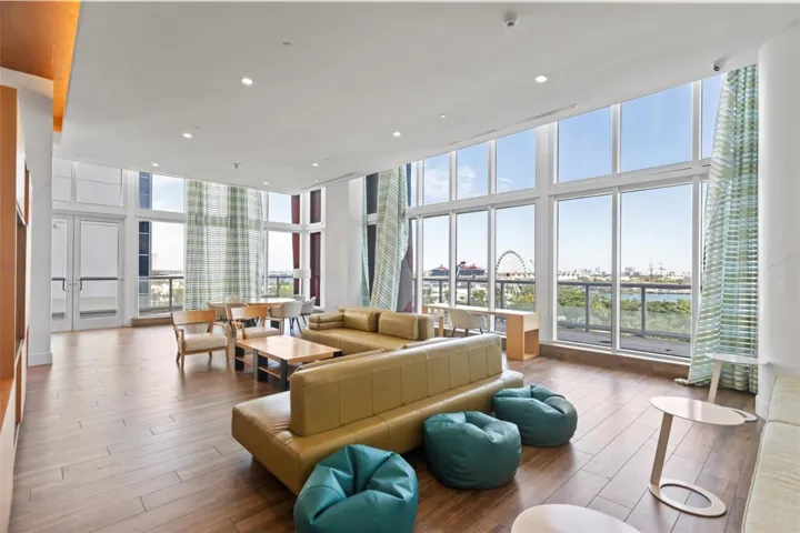 Expansive room featuring floor-to-ceiling windows, wood-finish flooring, recessed lighting, and balcony access