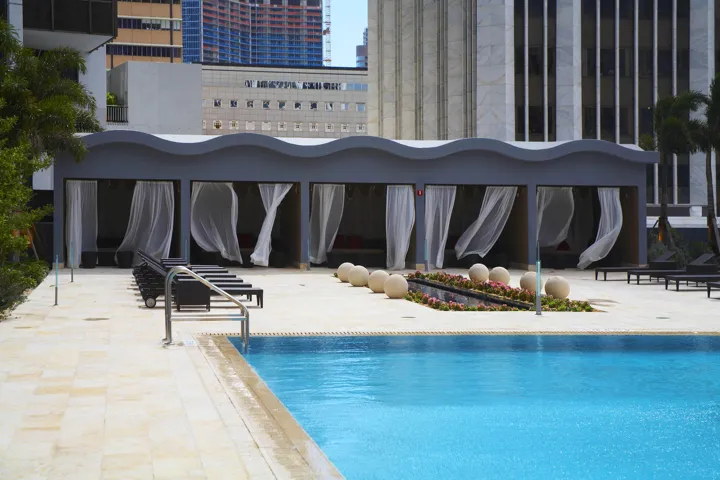 Resort-style pool with integrated cabanas, an accent water feature, and a surrounding paver deck