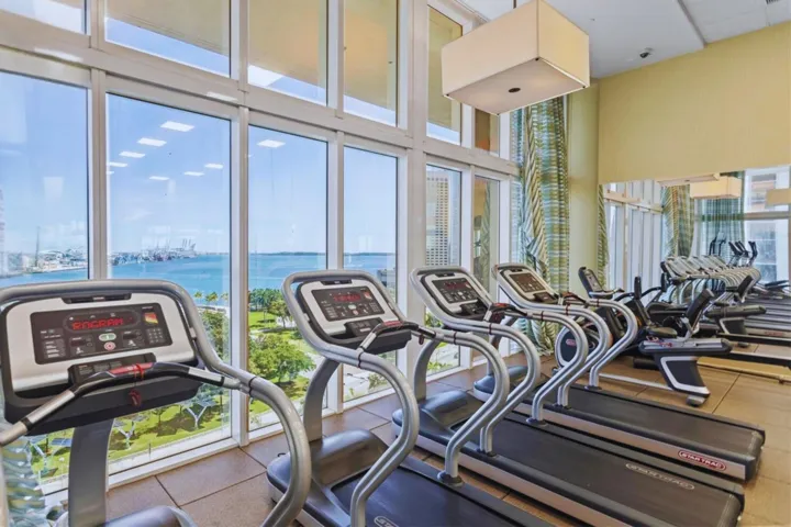 Floor-to-ceiling windows, water and city scenery, modern ceiling light fixture, tile flooring, full-wall mirror