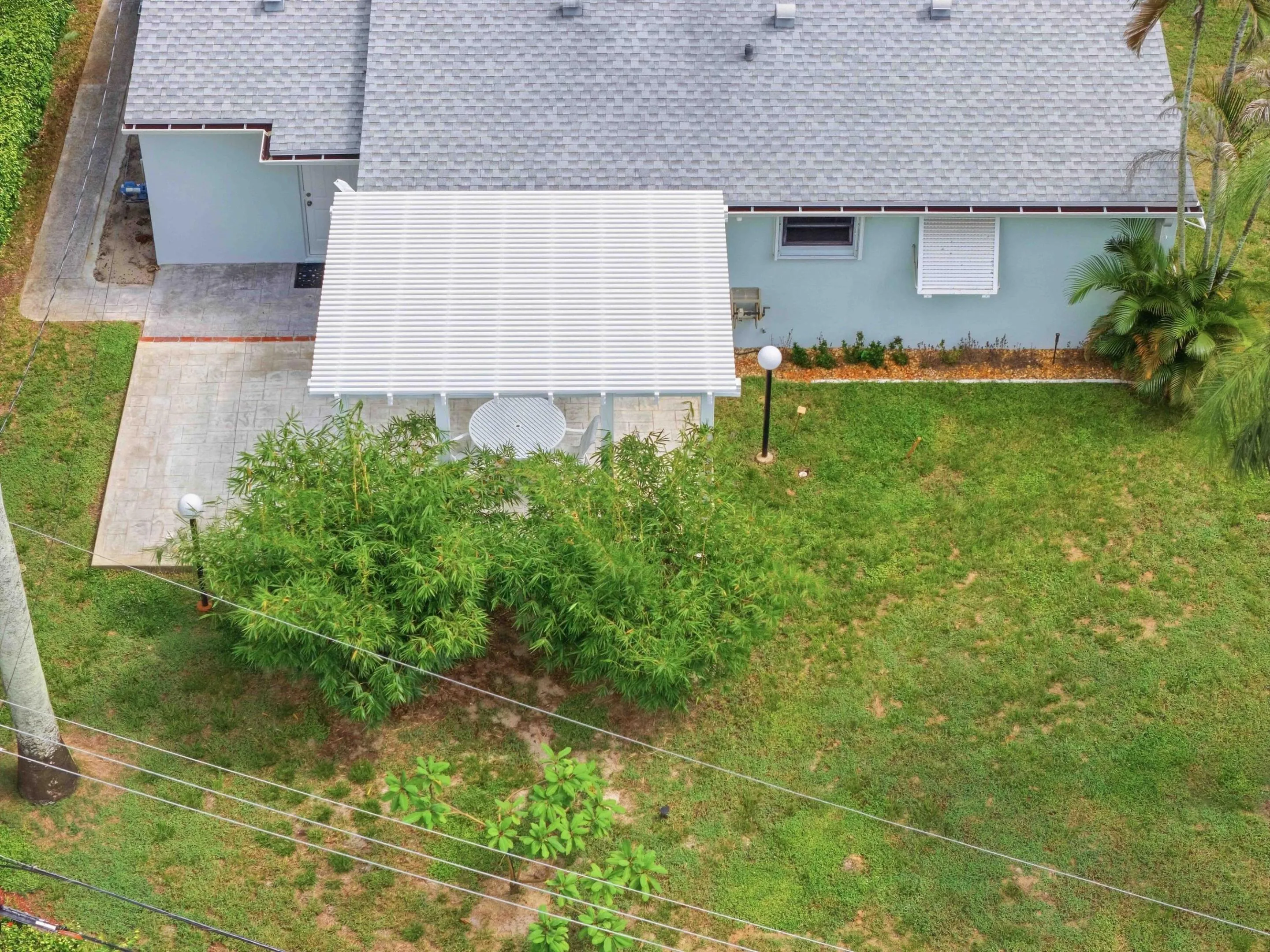 Expansive backyard featuring a manicured lawn, established landscaping, and a covered patio area with a white pergola