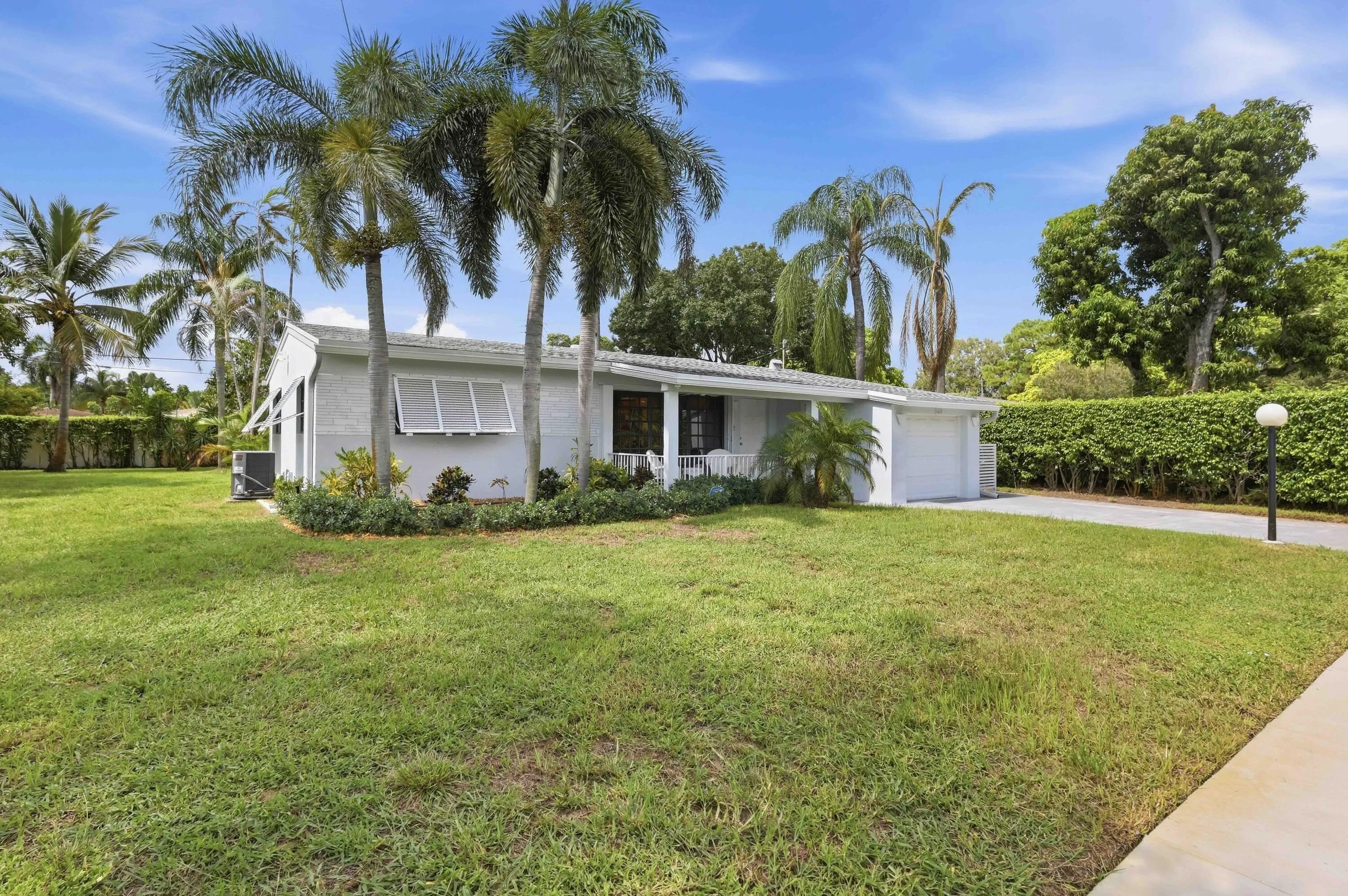 Single-story residence with a white exterior, attached garage, and a stamped concrete driveway