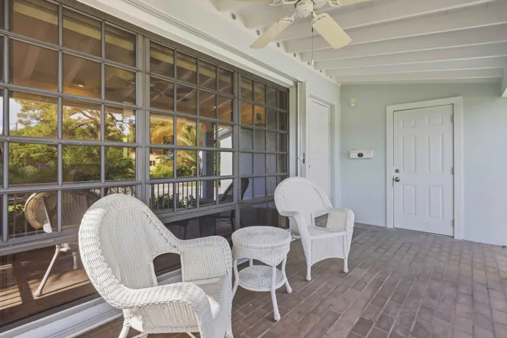 Covered patio with a brick-patterned floor, exposed beam ceiling, and a ceiling fan