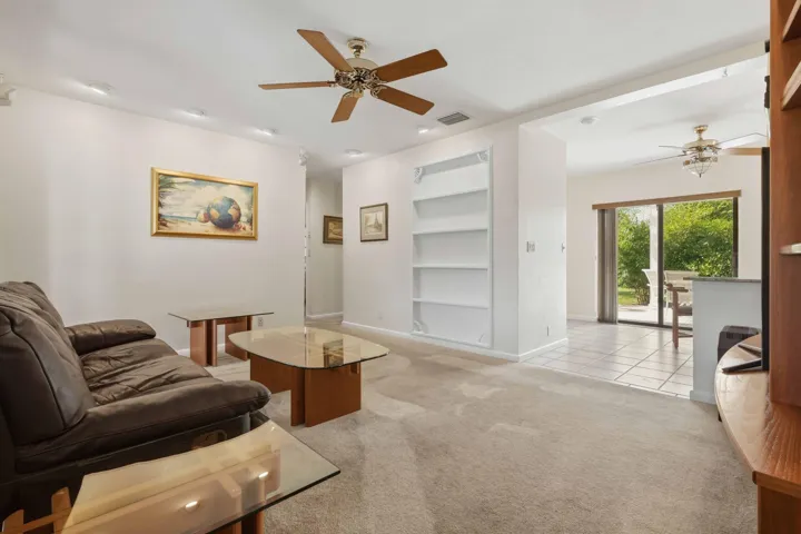 Recessed lighting, built-in shelving, wood-finish ceiling fan, sliding glass door, and tiled flooring