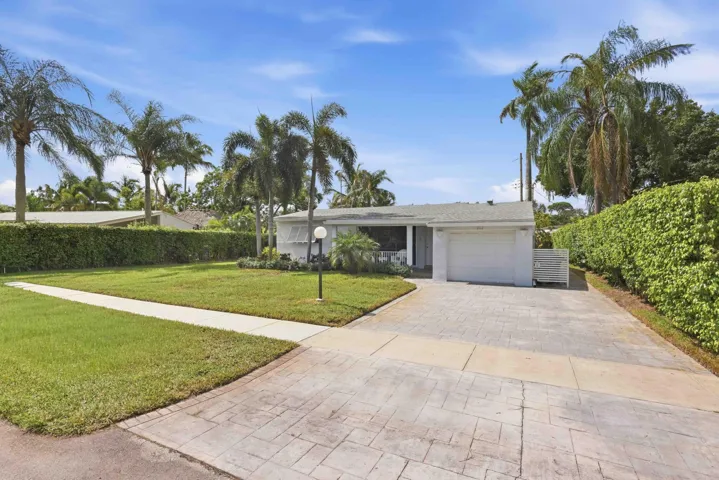 Single-story residence featuring a white exterior, attached garage, and lush green lawn