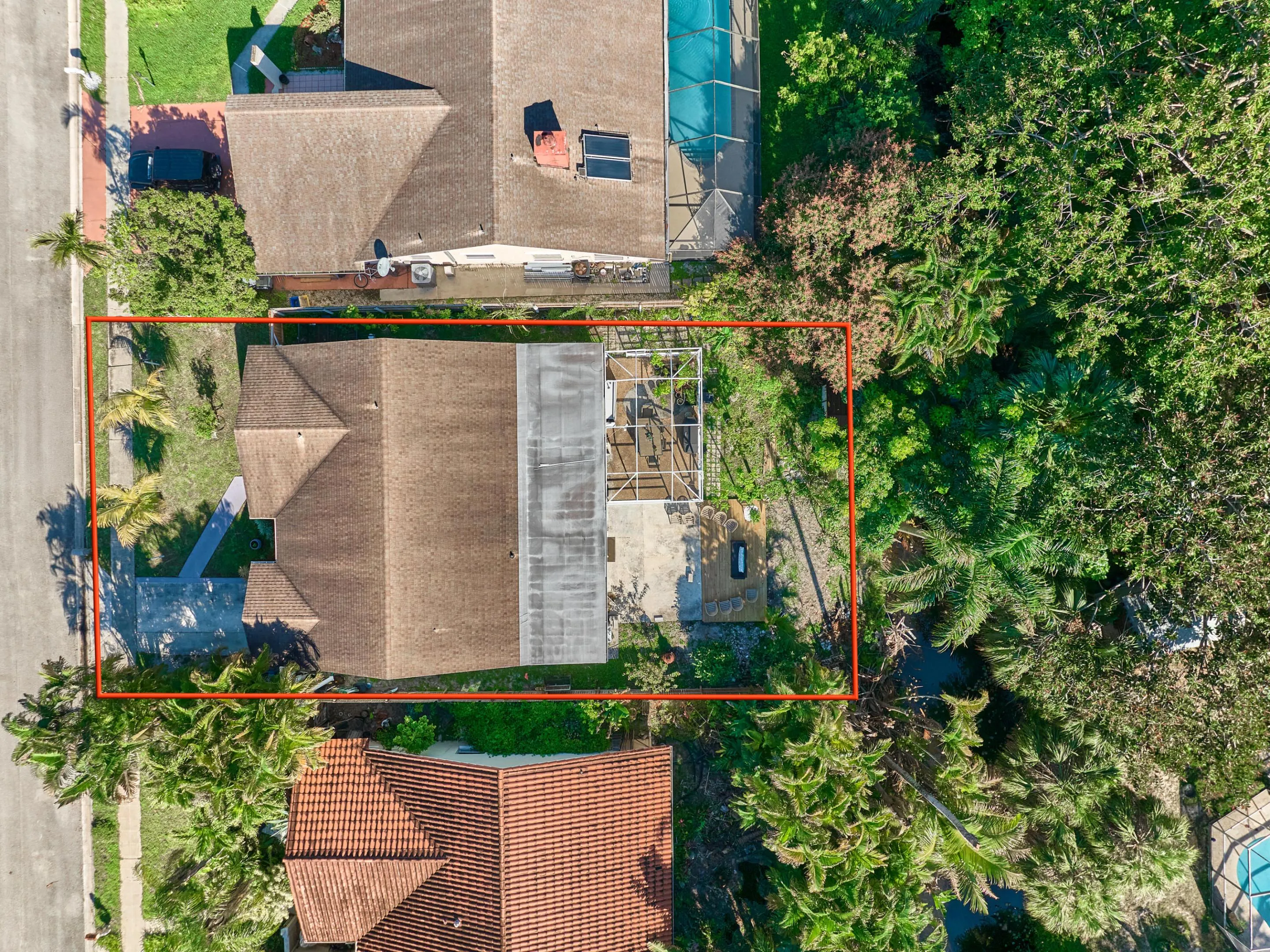 Gable roofline residence with a driveway, mature landscaping, and a screened outdoor structure