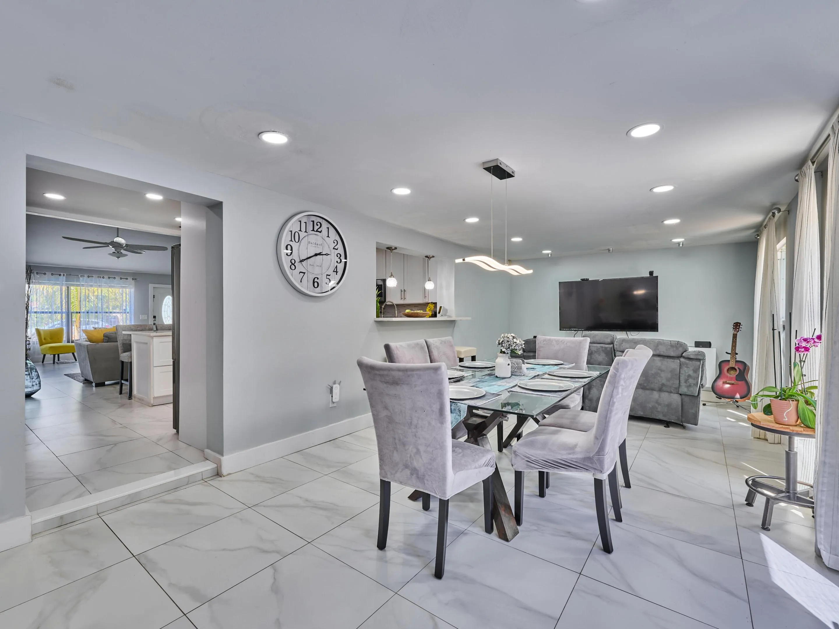 Recessed lighting throughout, tile flooring, modern pendant light fixture, and large windows with vertical blinds