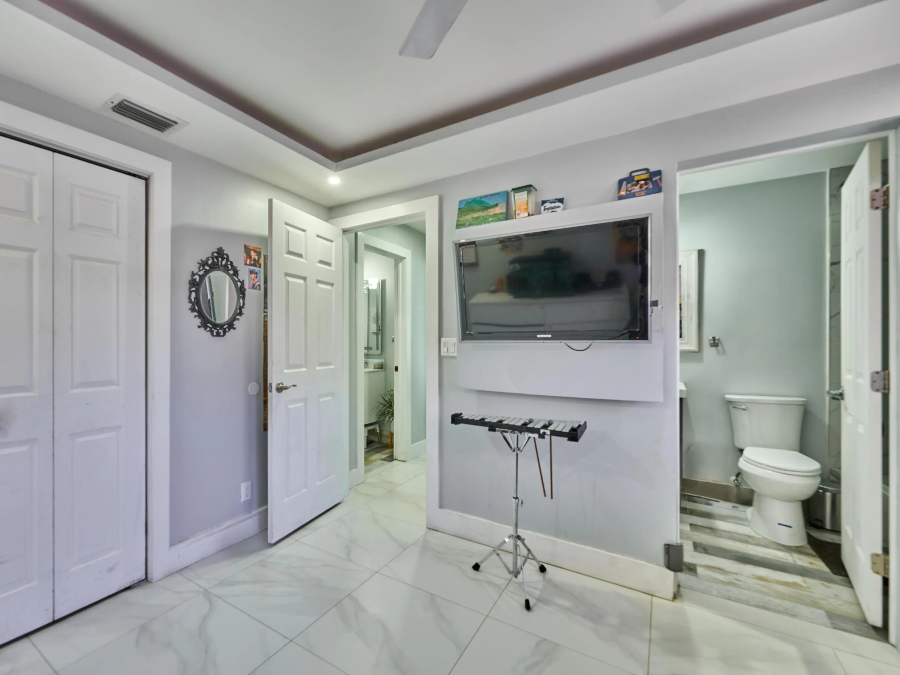 White tile flooring, recessed ceiling lighting, tray ceiling, white paneled doors, wall-mounted television