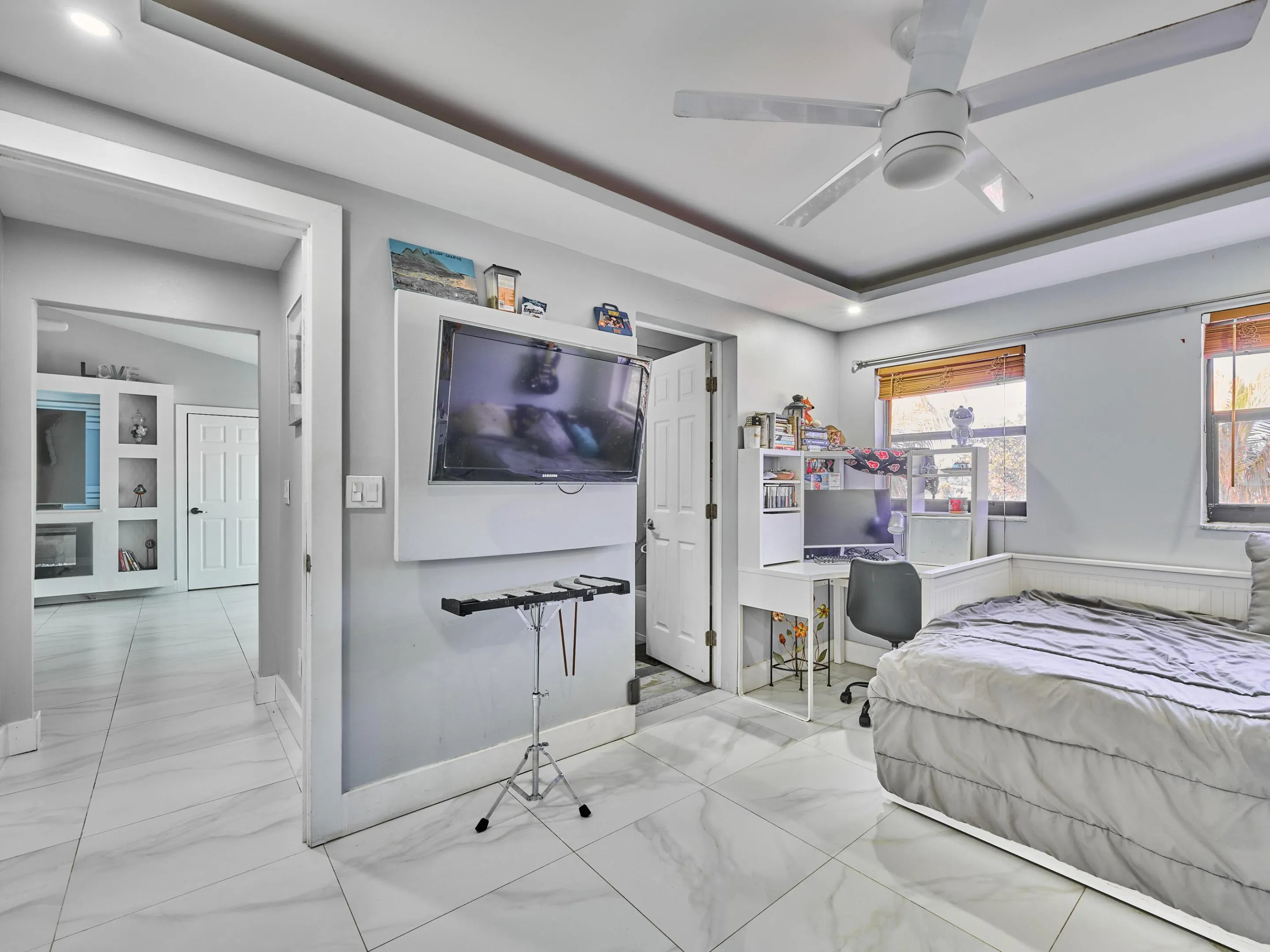 White tile flooring, tray ceiling, recessed lighting, ceiling fan, and built-in shelving