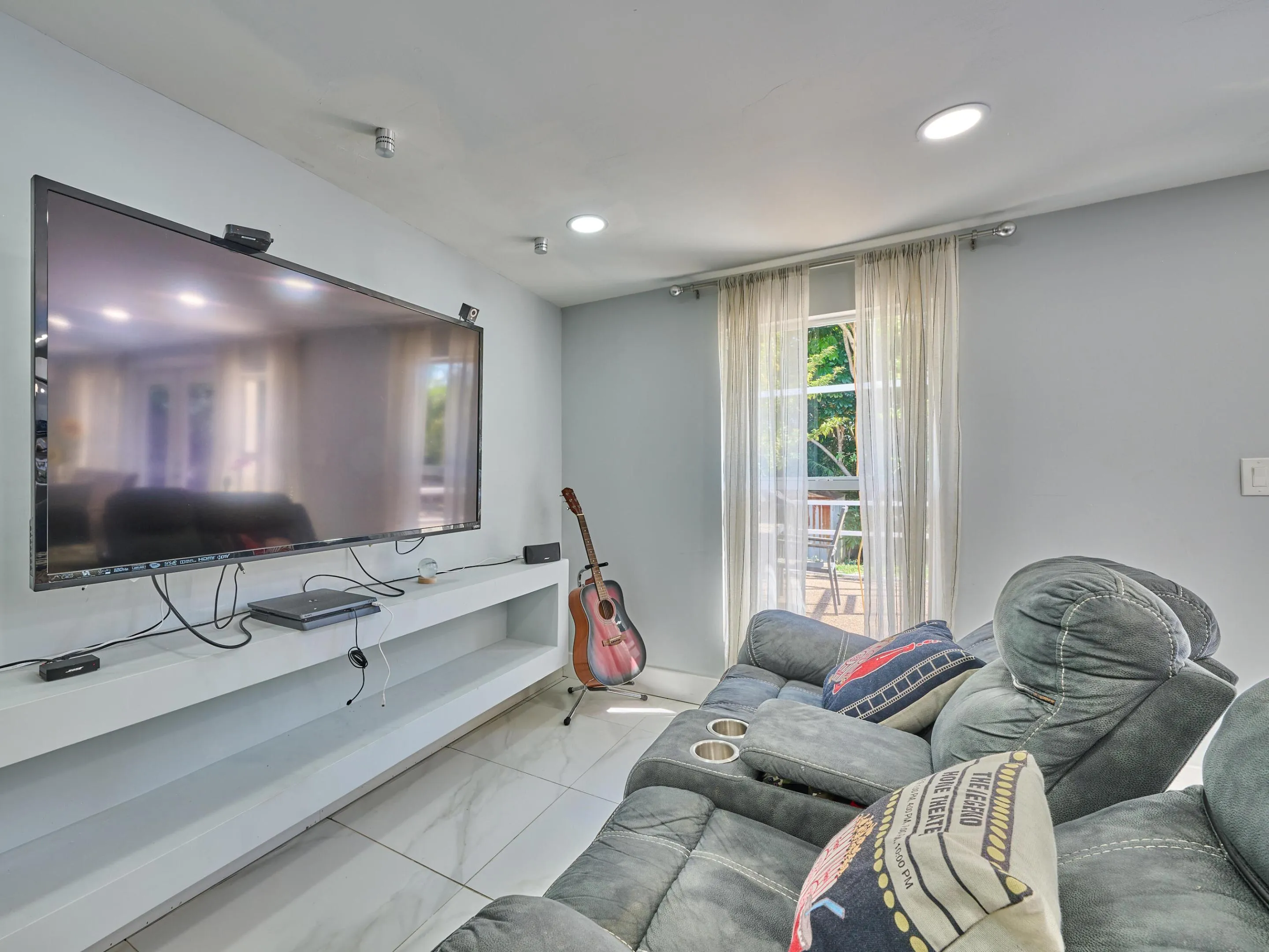 Recessed ceiling lighting, a large built-in media shelf, and tile flooring