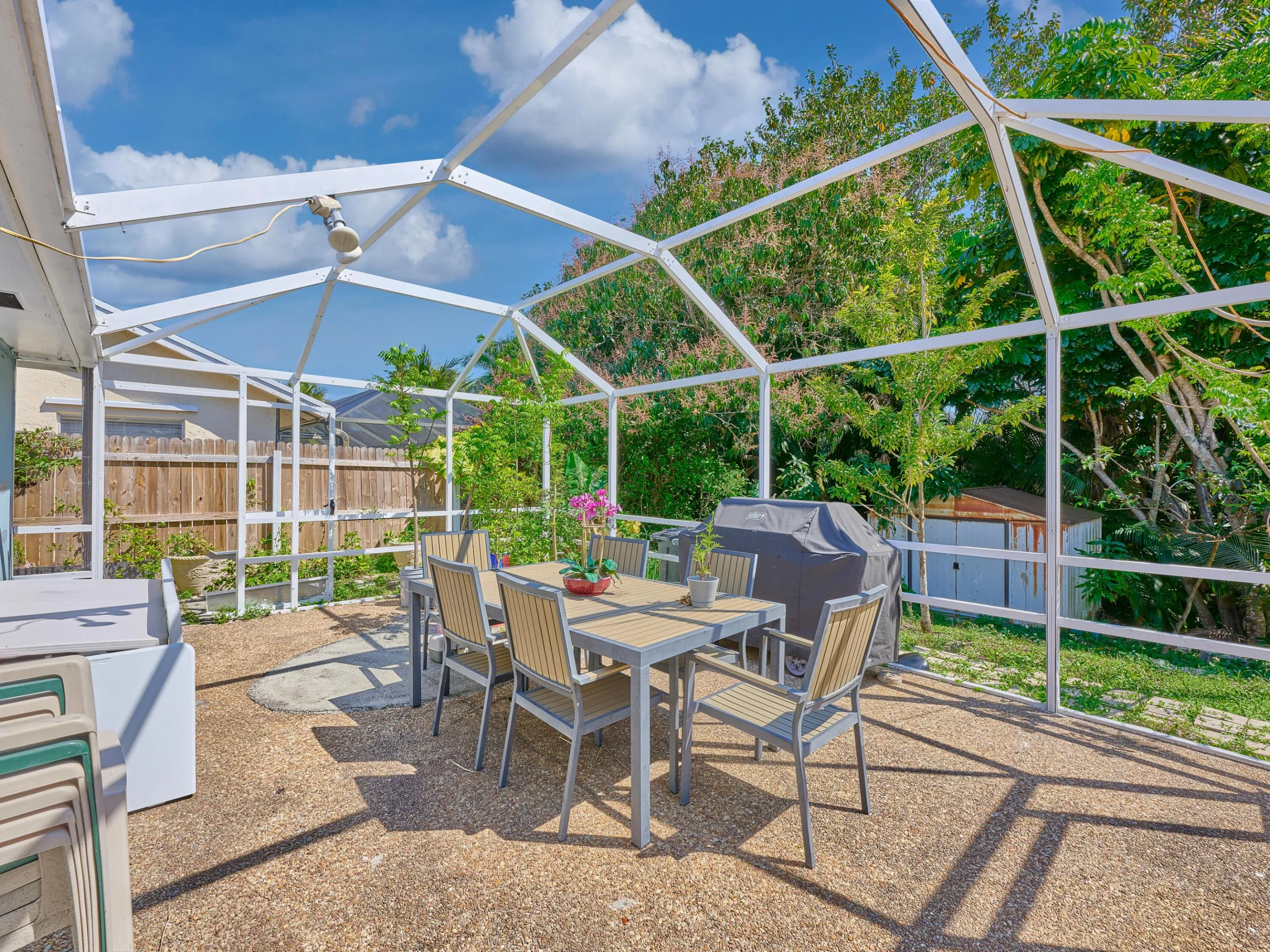 Screened outdoor living area with exposed aggregate concrete flooring and a partial privacy fence