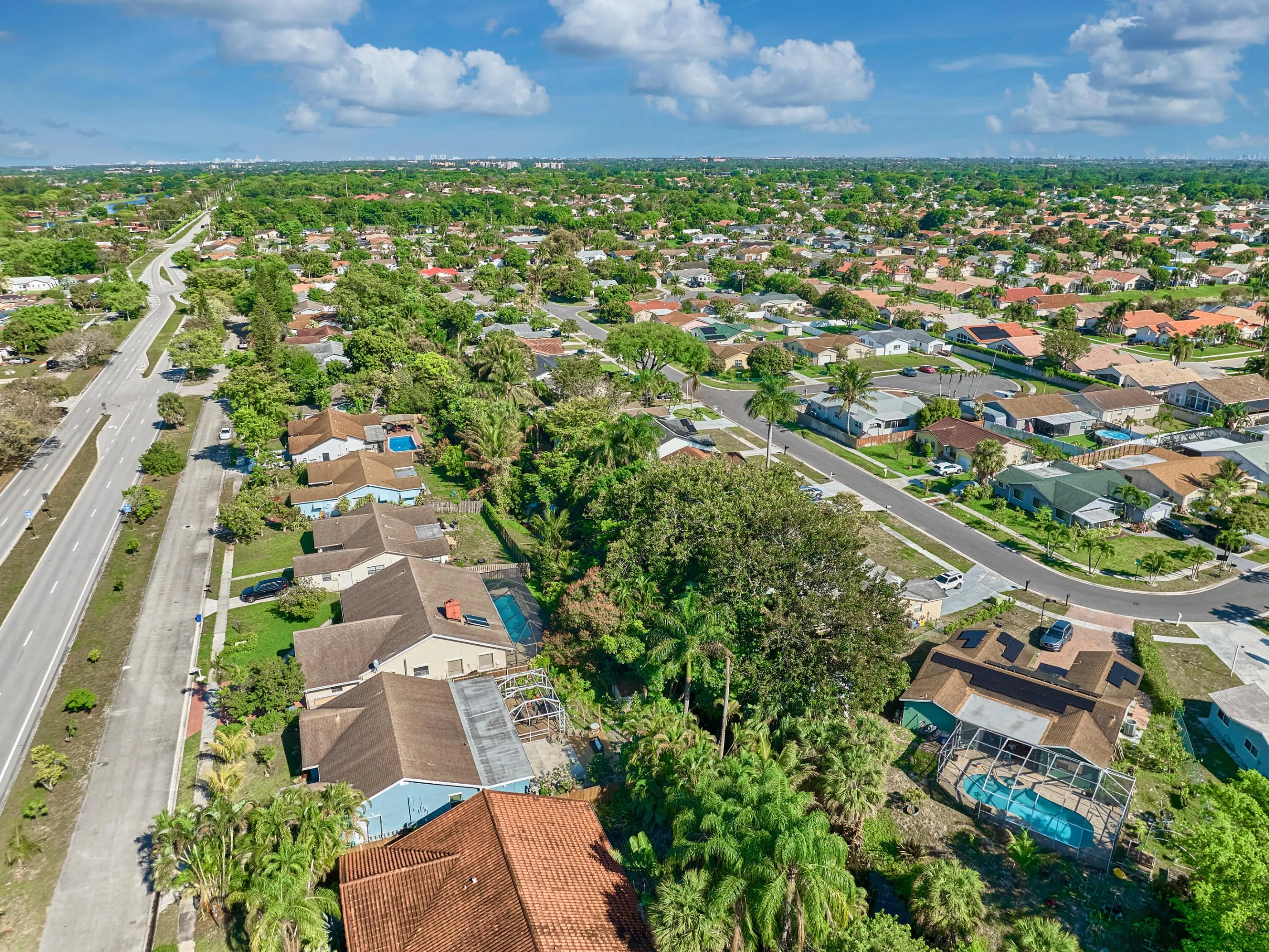 Expansive residential area featuring numerous single-story homes, mature trees, and a clear blue sky