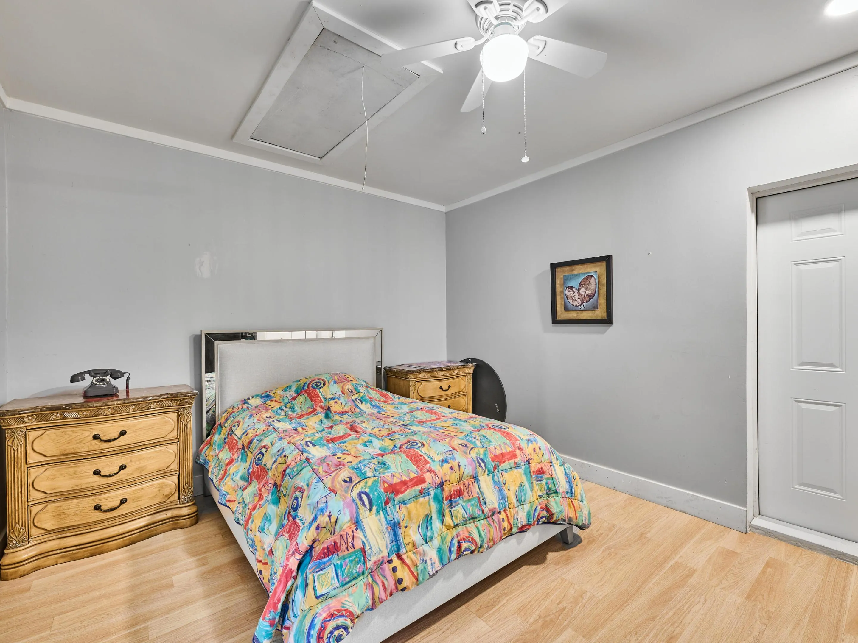 Bright secondary bedroom featuring wood-finish flooring, soft neutral wall finishes, and a ceiling fan with integrated lighting