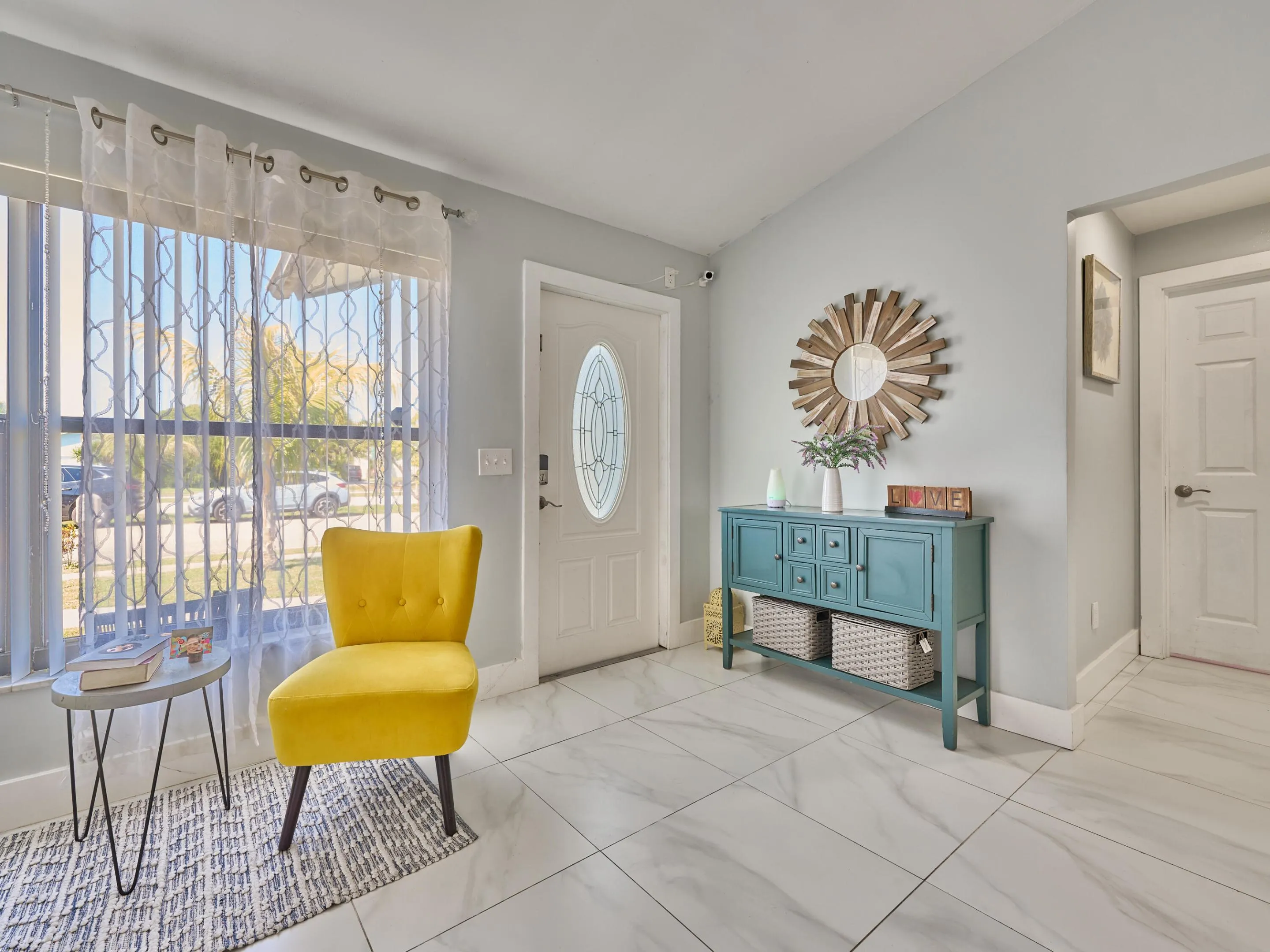 Entryway featuring large format tile flooring, a white paneled entry door with an oval glass insert, and a vaulted ceiling
