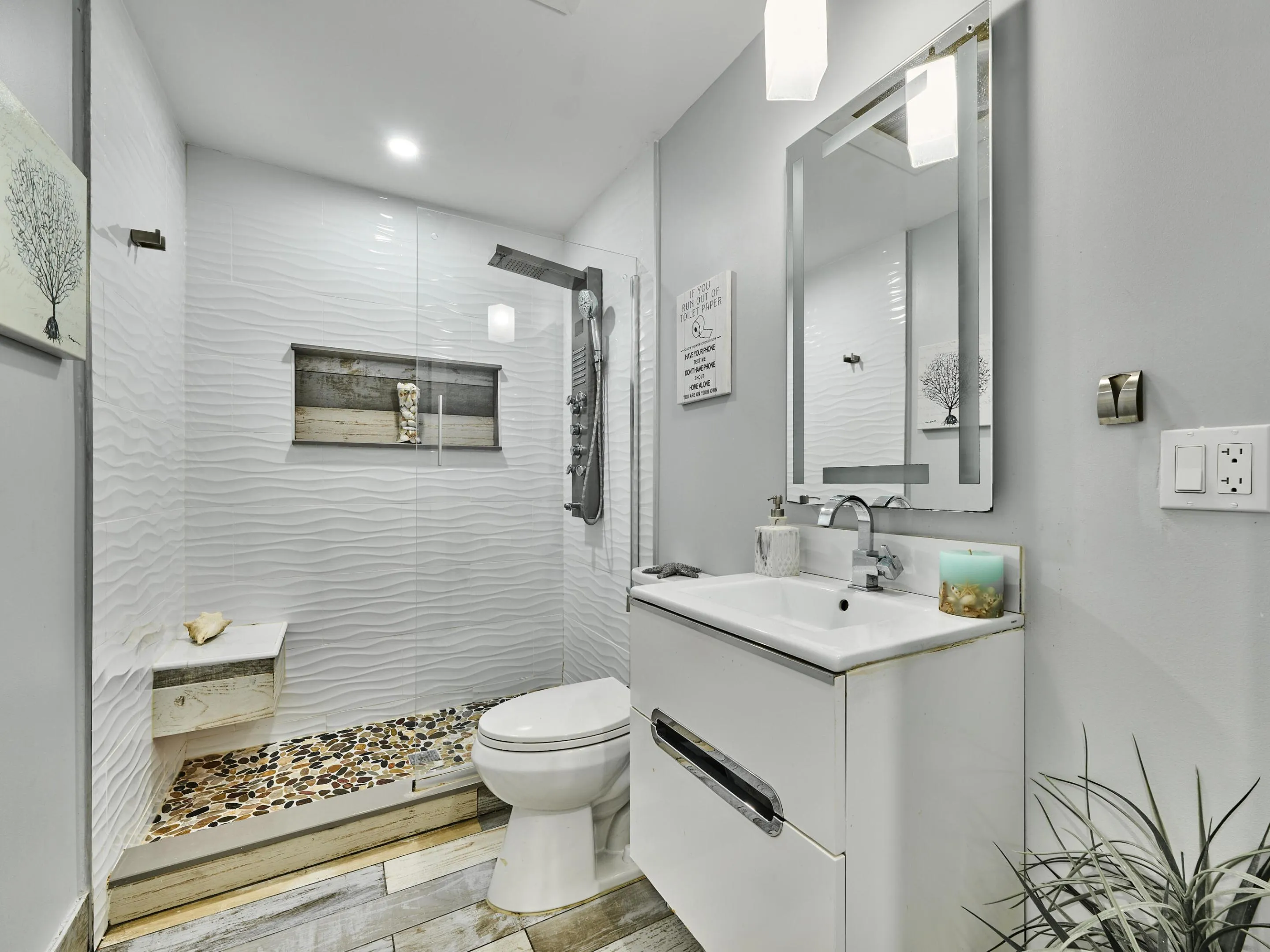 Walk-in shower with textured tile surround and pebble floor