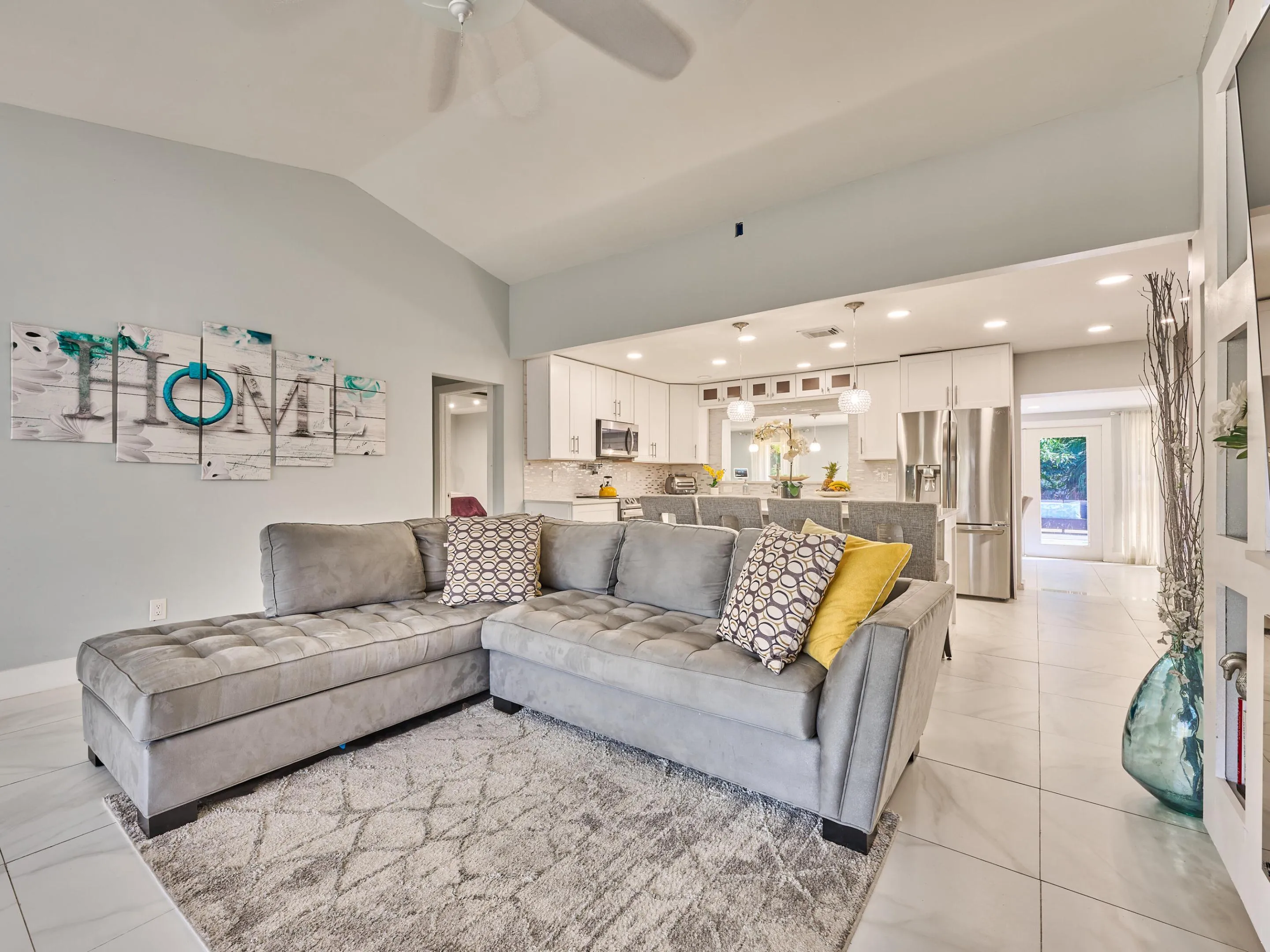 Vaulted ceiling, recessed lighting, white tile flooring, white shaker cabinetry, and stainless steel appliances