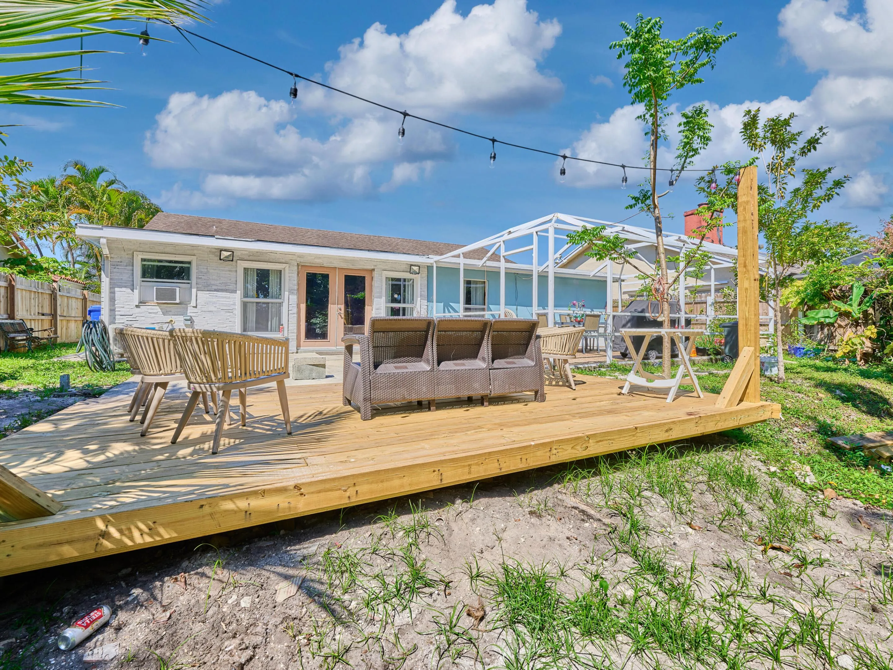 Expansive wooden deck with string lights, featuring a white exterior structure and a frame patio area